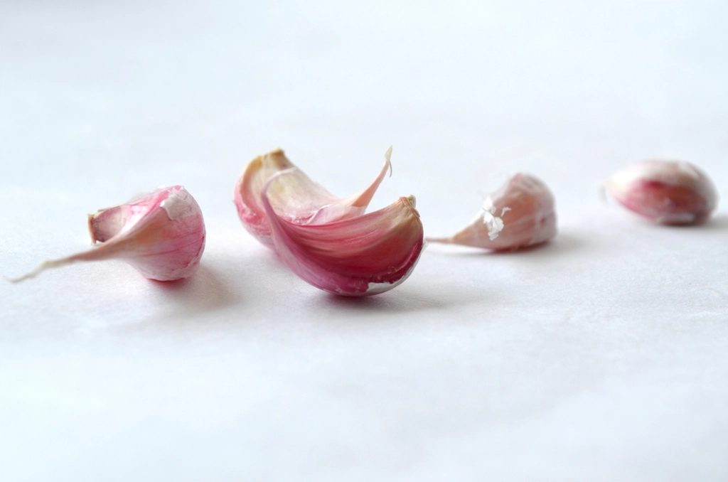 Freshly harvested garlic bulbs with dried stems and roots, resting together on a rustic surface
